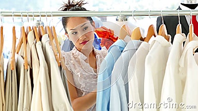 Modedesigner, der durch ihre Kleidungsschiene schaut Modedesigner, der durch ihre Kleidungsschiene schaut