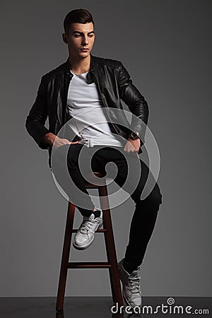 Model in black posing seated on stool while resting Stock Photo