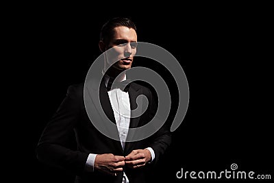 Model in black tux with bowtie posing in dark studio Stock Photo