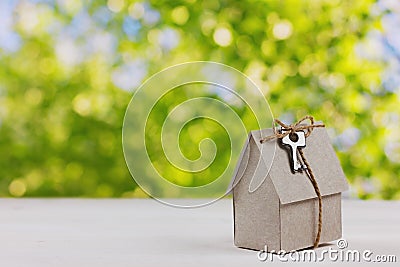 Model of cardboard house with a bow of twine and key against green bokeh background. Stock Photo