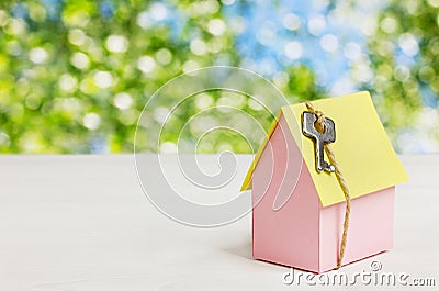 Model of cardboard house with a bow of twine and key against green bokeh background. house building, loan, real estate or buying Stock Photo