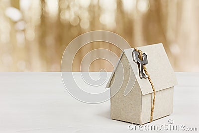 Model of cardboard house with key against bokeh background. house building, loan, real estate or buying a new home Stock Photo