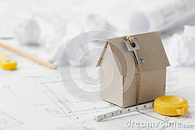 Model cardboard house with key and tape measure on blueprint. Home building, architectural and construction design concept Stock Photo