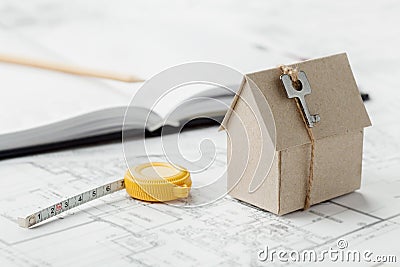 Model cardboard house with key and tape measure on blueprint. Home building, architectural and construction design concept Stock Photo