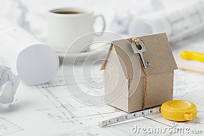 Model cardboard house with key and tape measure on blueprint. Home building, architectural and construction design concept Stock Photo