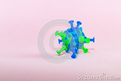 A model of a coronavirus bacterium made of blue green plasticine on a pink paper background. Topic protection, danger from the spr Stock Photo