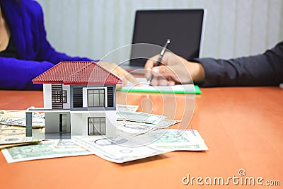 Model house on money and Businessman signing documents on the table, New home and real estate concept Stock Photo