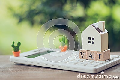 A model house model is placed on wood word VAT . as background property real estate concept with copy space for your text or Stock Photo