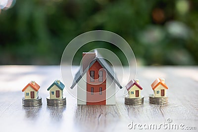 Model houses and houses on a pile of coins Planning ideas for real estate investing, saving and buying homes, mortgages Stock Photo