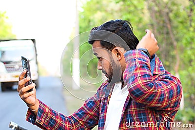 Model looking at his mobile and shorting his shirt Stock Photo