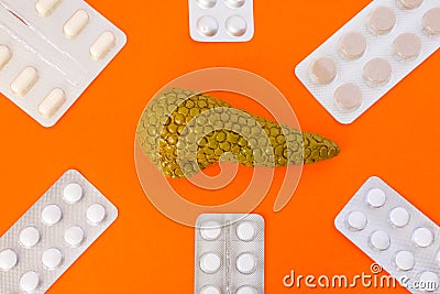 Model of pancreas gland surrounded by six blister packs with white pills on orange background. Photo concept art of treatment or Stock Photo