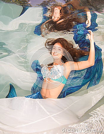 Model in a pool wearing a mermaid`s tail. Stock Photo