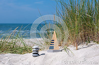 Model of a sailboat and a pile of stones in the sand dunes. Stock Photo