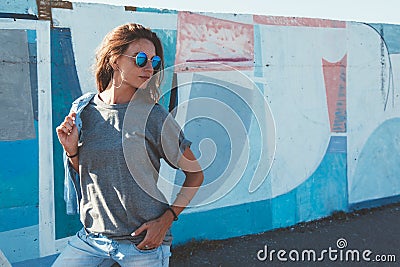 Model wearing plain tshirt and sunglasses posing over street wall Stock Photo