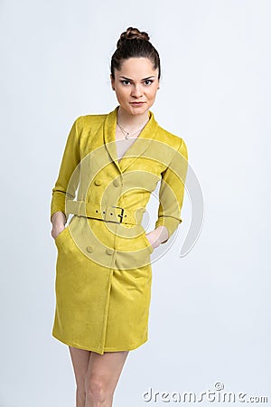 Model in yellow coat with belt, white sandals with silver chain and pendant on neck, isolated on white background. Stock Photo