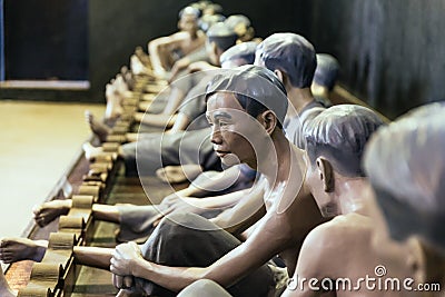 Models of detained prisoners by lock their foot ankle on something like wooden console at Hoa Lo Prison Museum in Hanoi, Vietnam Editorial Stock Photo