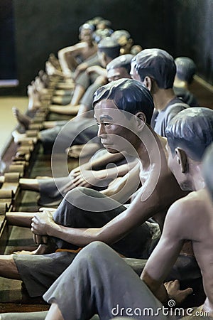 Models of detained prisoners by lock their foot ankle on something like wooden console at Hoa Lo Prison Museum in Hanoi, Vietnam Editorial Stock Photo