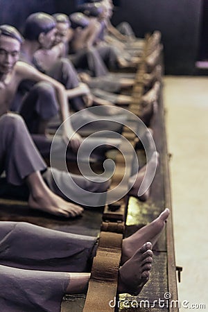 Models of detained prisoners by lock their foot ankle on something like wooden console at Hoa Lo Prison Museum in Hanoi, Vietnam Editorial Stock Photo