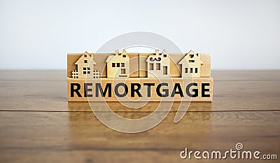 Models of a wooden house. Word `remortgage` on wooden block. Copy space. Business concept. Beautiful wooden table, white Stock Photo