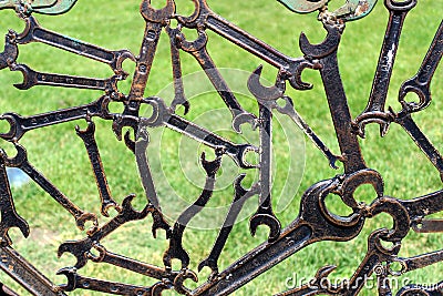 Modern abstract industrial background from welded metal spanners with grass behind. Stock Photo