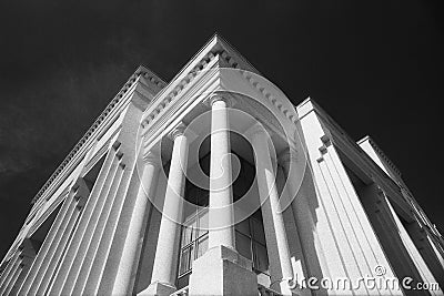 Modern architecture concept. Black and white grainy image of impressive building with columns against black sky Stock Photo