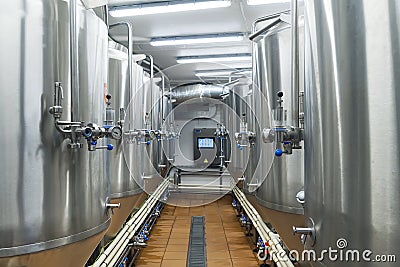 Modern automated beer factory. Lines of metal tanks in modern brewery. Shopfloor with brewery facilities. Manufacturable process o Stock Photo