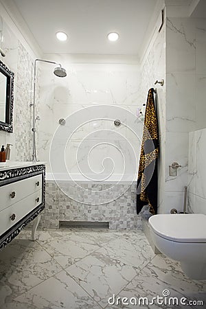 Modern bathroom with marble tiles, luxurius wardrobe and white toilet Stock Photo