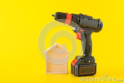 Modern black cordless screwdriver with rechargeable battery and wooden house Stock Photo