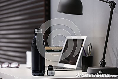 Modern black thermos bottle on table in office Stock Photo