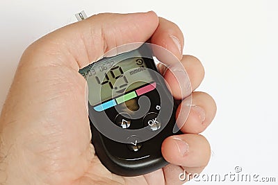 Modern blood glucose meter held in left hand with healthy person preprandial glucose value Stock Photo