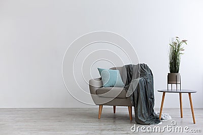 Modern boho cozy corner of home. Gray vintage armchair with blue pillow and blanket Stock Photo