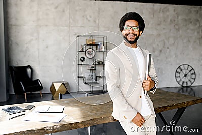 A modern Brazilian businessman stands poised with his laptop, his smart attire and relaxed demeanor Stock Photo