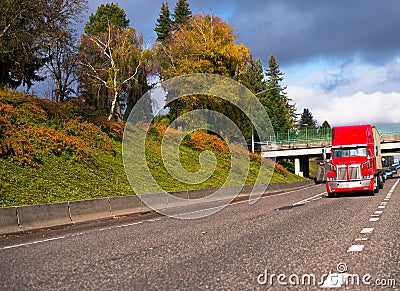 Bright red big rig semi truck transporting container on flat bed Stock Photo