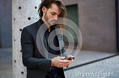 Outdoor portrait modern business guy in black suit using a smartphone for connection and chatting Stock Photo