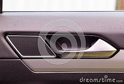 Modern car door trim with tweeter and door handle with metal insert, close-up Stock Photo