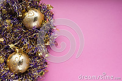 Modern Christmas decorations, golden baubles ornaments on purple tinsel and pink background. Merry Christmas and Happy New Year Stock Photo