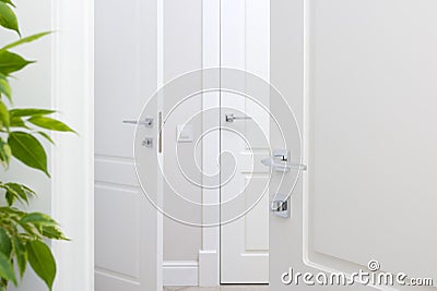 Modern chrome door handle on white door. Beautiful interior closeup Stock Photo