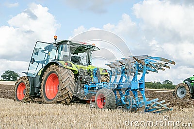 Modern claas tractor pulling a plough Editorial Stock Photo