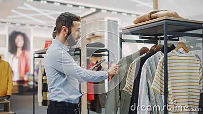 Modern Clothing Store: Male Visual Merchandising Professional Uses Digital Tablet Computer To Create Stock Photo