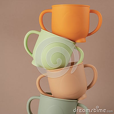 Modern colorful pastel silicone cups stacked in column on brown background. Baby tableware, first feeding. Stock Photo