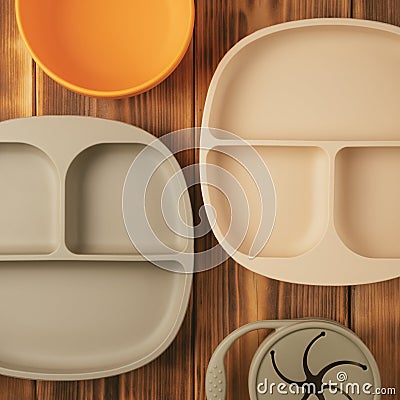 Modern colorful pastel silicone food trays, bowl and snack cup on brown wooden table. Baby tableware, first feeding. Stock Photo