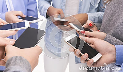 Group of millennials using cellphones, standing in circle Stock Photo