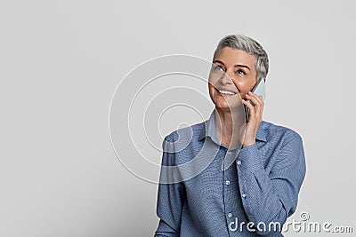 Modern Communication. Smiling Middle-Aged Businesswoman Talking On Cellphone Over Light Studio Background Stock Photo