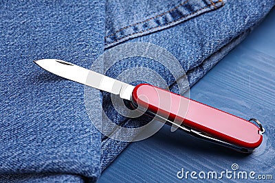 Modern compact portable multitool and jeans on blue wooden table Stock Photo