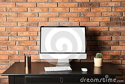 Modern computer monitor on desk brick wall, mock up with space for text Stock Photo