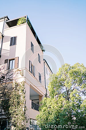 Modern concrete facade of a multi-storey building with terraces surrounded by trees Stock Photo