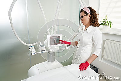 Beautiful beautician operating cosmetology equipment in modern beauty clinic. Spa concept Stock Photo