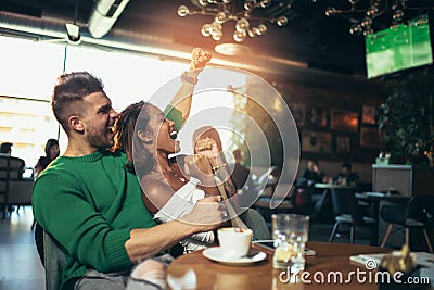 Modern couple in cafe looking football match on tv in cafe. Stock Photo