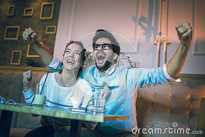 Modern couple in cafe looking football match on tv in cafe. Stock Photo