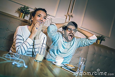 Modern couple in cafe looking football match on tv in cafe. Stock Photo